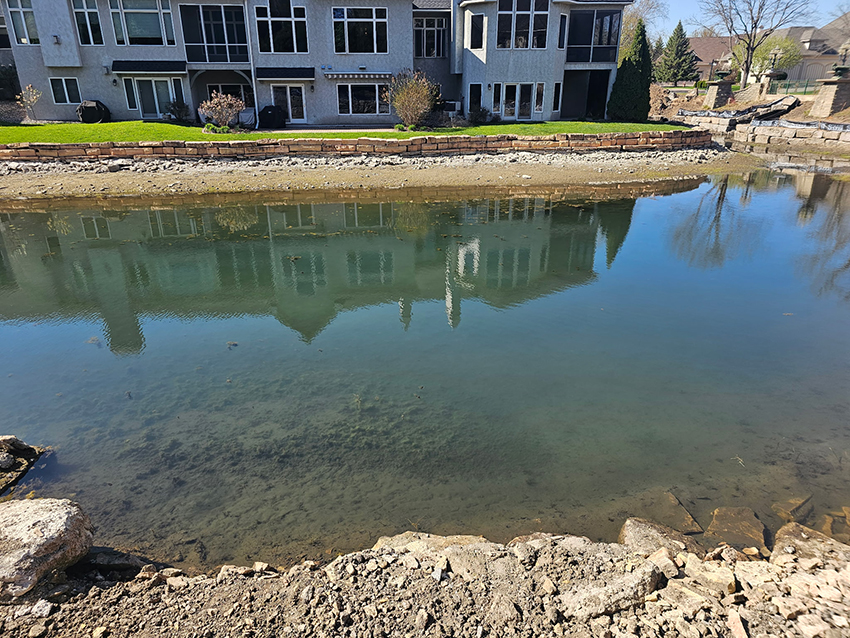 Eroded lakeshore bank behind a residential home before shoreline restoration by Triple Landscaping